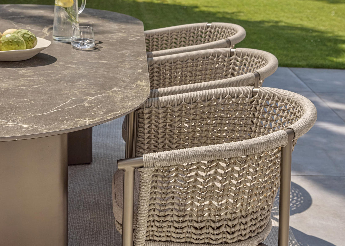 Apple Bee Pulau dining tuinstoelen Champagne aan een ovale dining tuintafel met keramisch blad