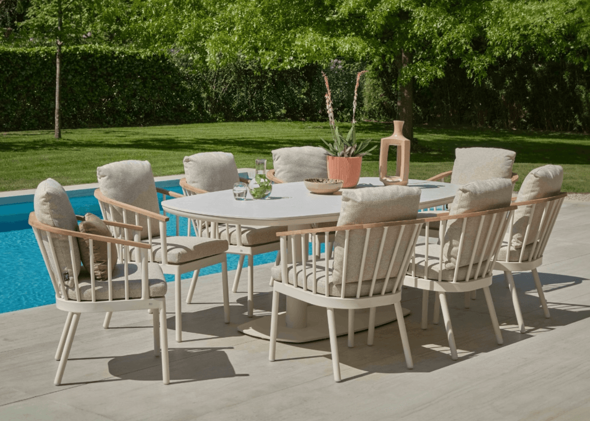 Apple Bee Zanzibar Dining Tuintafel 220 cm Cintered Stone Oyster met comfortabele stoelen bij een zwembad.