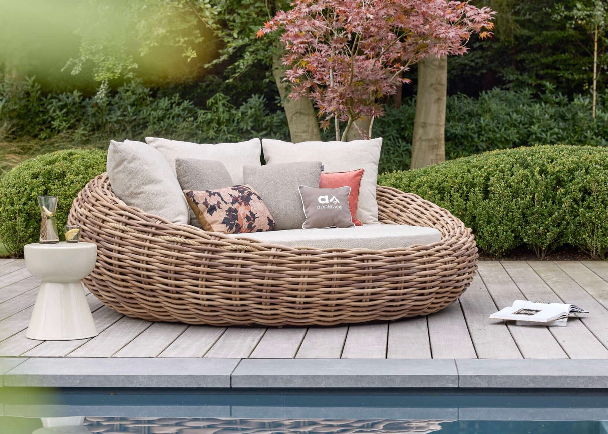 Apple Bee Cocoon loungeset op een houten terras bij het zwembad met kussens en decoratief meubilair.